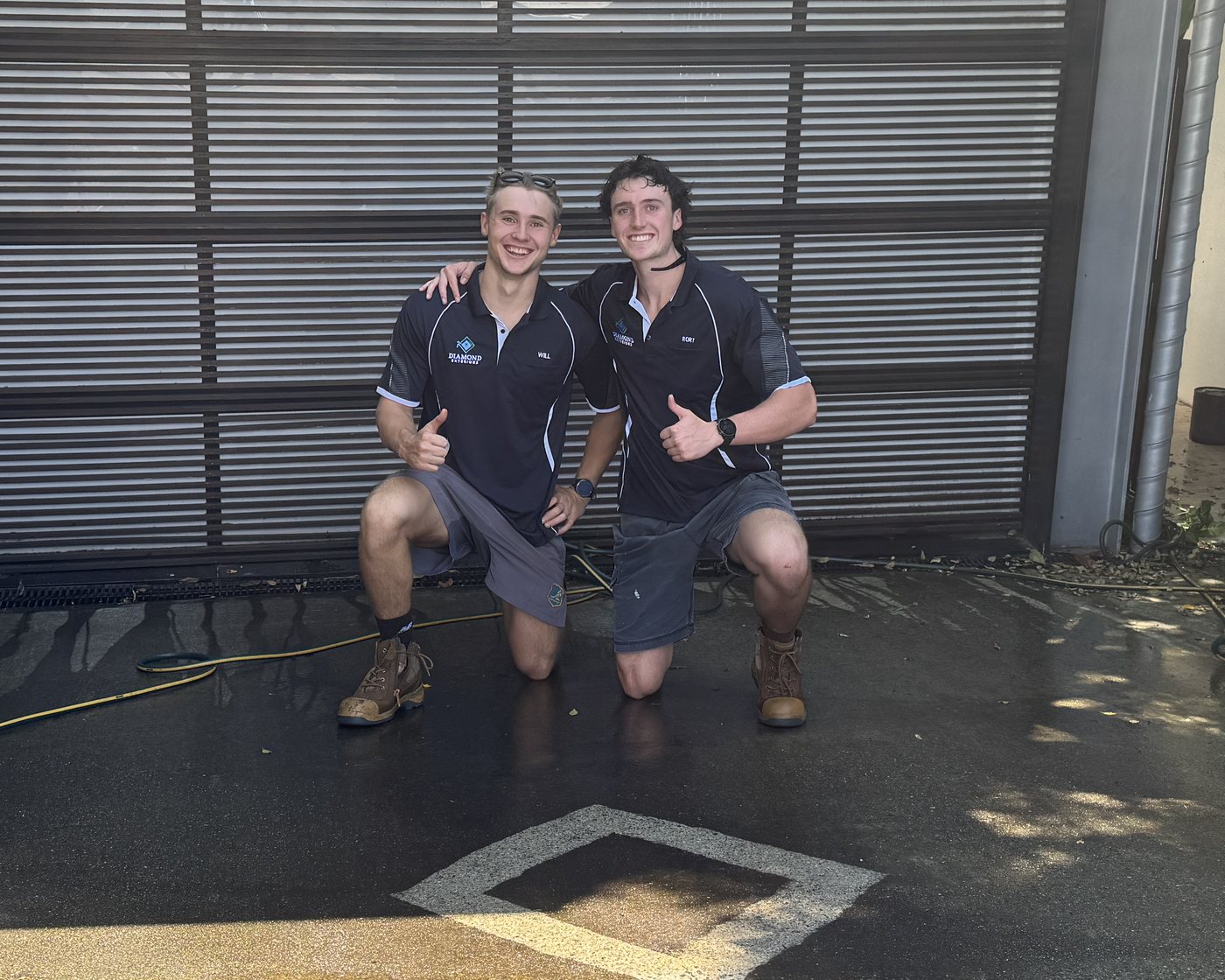 Will (left) and Rory kneeling on a freshly cleaned driveway, giving a thumbs up